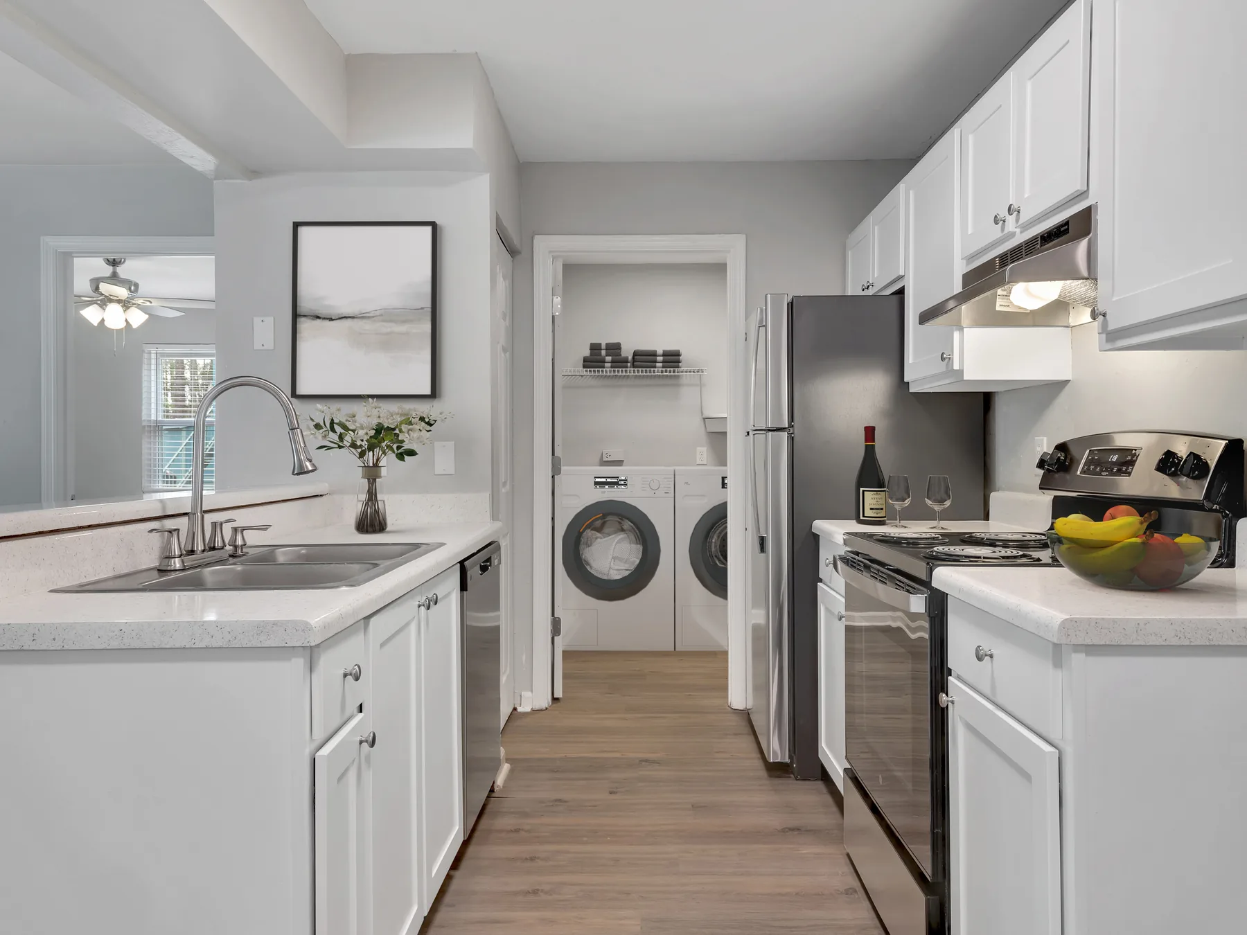Renovated kitchen with white cabinets, stainless appliances and laundry room with washer and dryer at Crescent Ridge